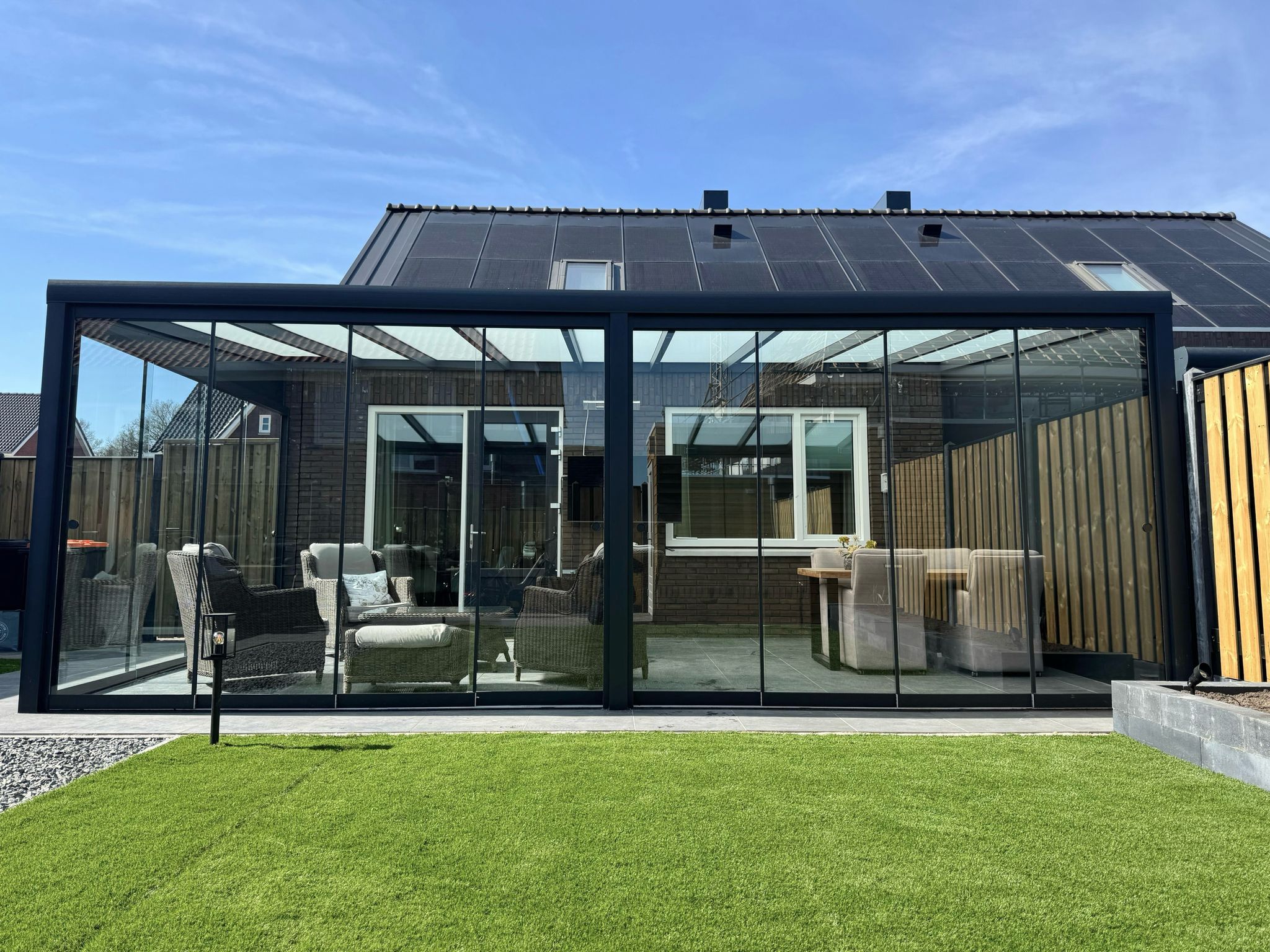 Aluminium veranda met glazen dak en schuifwanden, gerealiseerd in Enter