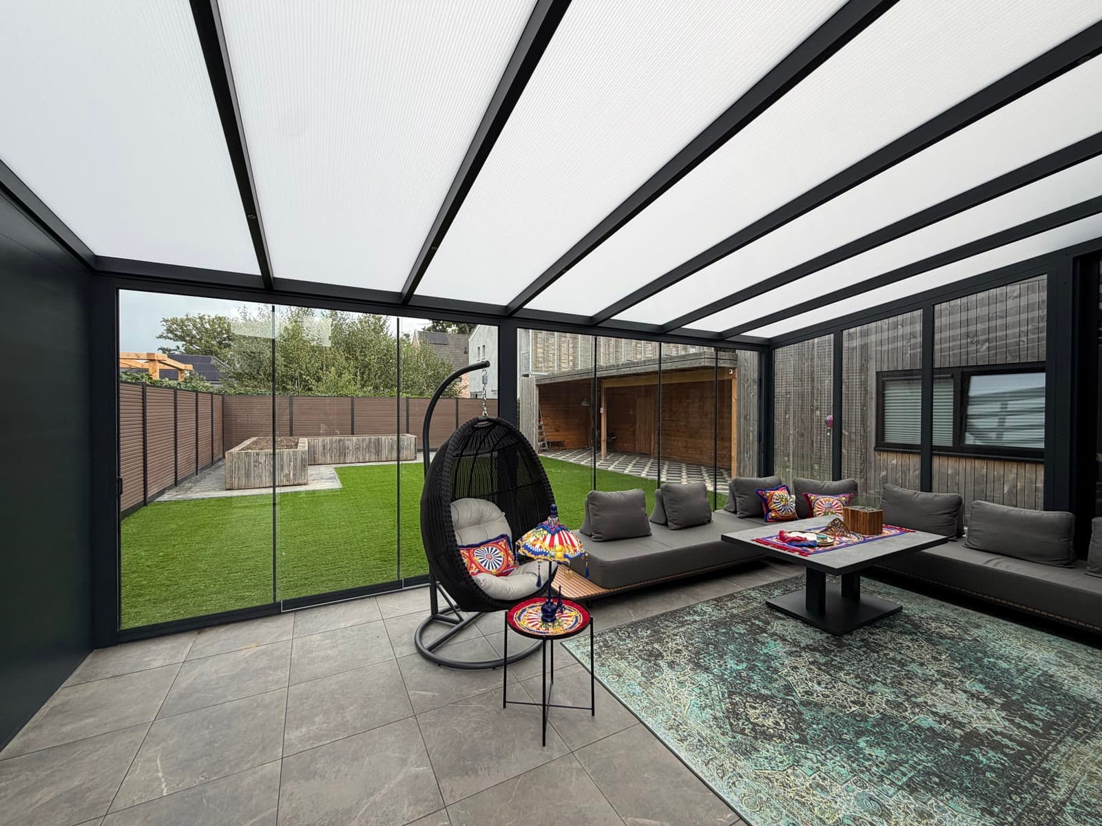 Aluminium veranda dichtgemaakt met glazen schuifwanden en een aluminium zijwand